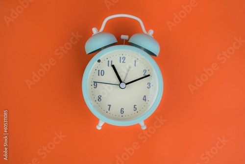 Blue alarm clock isolated on an orange background. Time concept.