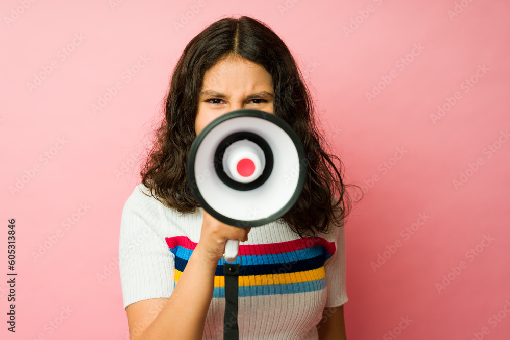 Fototapeta premium Annoyed teen girl looking angry using a megaphone screaming