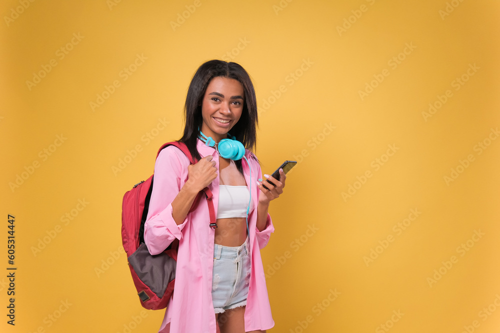 Obraz premium African American student woman using smartphone standing over isolated yellow background with a happy face standing and smiling with a confident smile