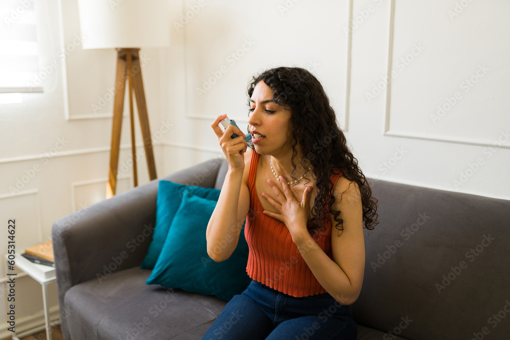 Latin young woman with an asthma attack using an inhaler Latin young woman with an asthma attack using an inhaler