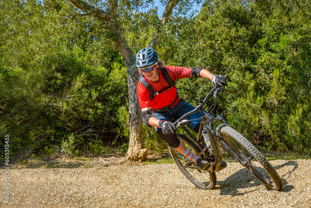 Naklejka premium Mountain biker takes a turn at an angle and in a professional position. Sporty and dynamic image that reproduces enduro mountain biking