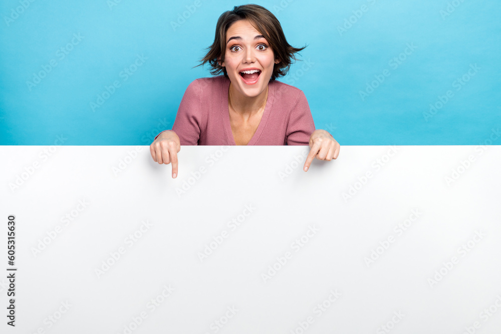 Photo of young crazy woman indicating fingers empty space banner crazy proposition product placement isolated on blue color background - obrazy, fototapety, plakaty 