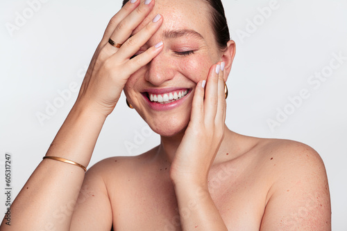 Happy woman with clean skin touching face