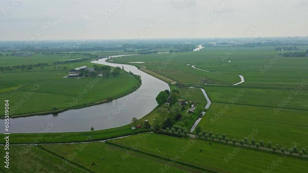 Aerial of farms located near a river surrounded by green pastures in the Netherlands Aerial of farms located near a river surrounded by green pastures in the Netherlands