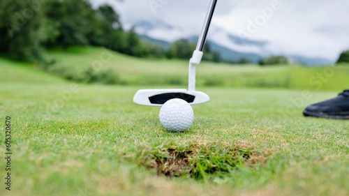 Golfer putting golf ball on the hole