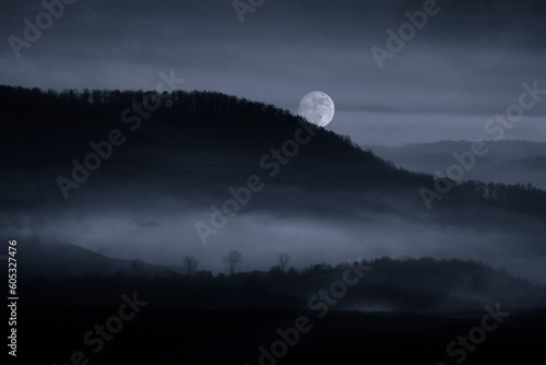 full moon rising over misty...