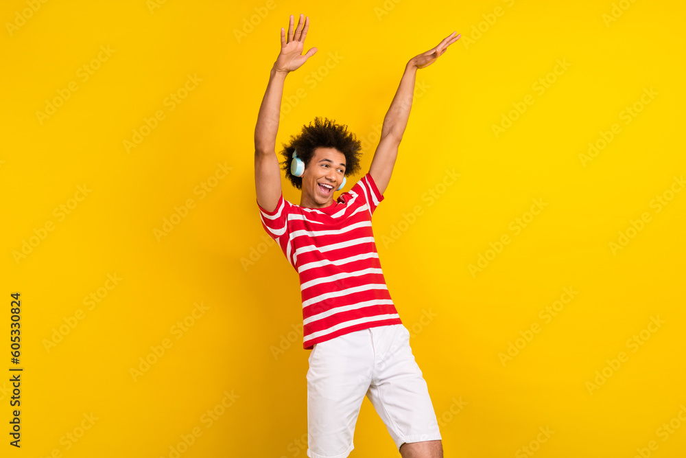 Photo of cool cheerful man wear striped t-shirt listening headphones having fun isolated yellow color background Photo of cool cheerful man wear striped t-shirt listening headphones having fun isolated yellow color background