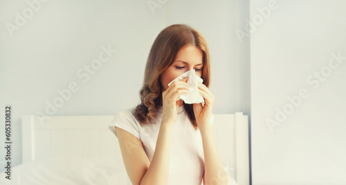 Fotografia Portrait of sick upset woman sneezing blow nose using tissue