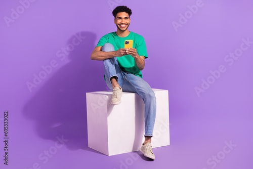 Full body cadre of young man platform box using smartphone gadget apple useful tips for comfort use isolated on purple color background