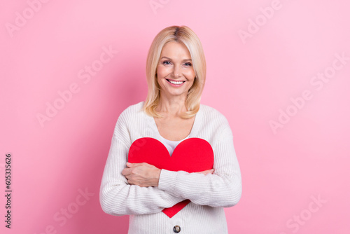Photo of good mood adorable senior woman with bob hairdo wear knit cardigan hugging big paper heart isolated on pink color background © deagreez