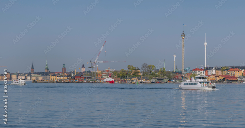 Commuter boats leaving piers for the archipelago, the old town Gamla Stan, the 
wharf island Beckholmen, towers,  Tivoli in the background, a tranquil sunny summer day in 
Stockholm