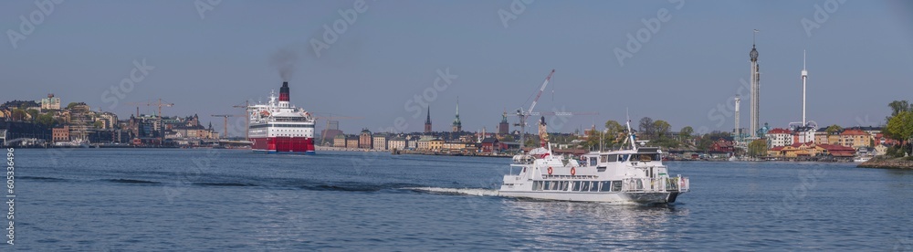 A cruise RORO ferry arriving at the ferry terminal, an inner archipelago commuting ferry passing on the 
way from down town piers, a tranquil sunny summer day in Stockholm