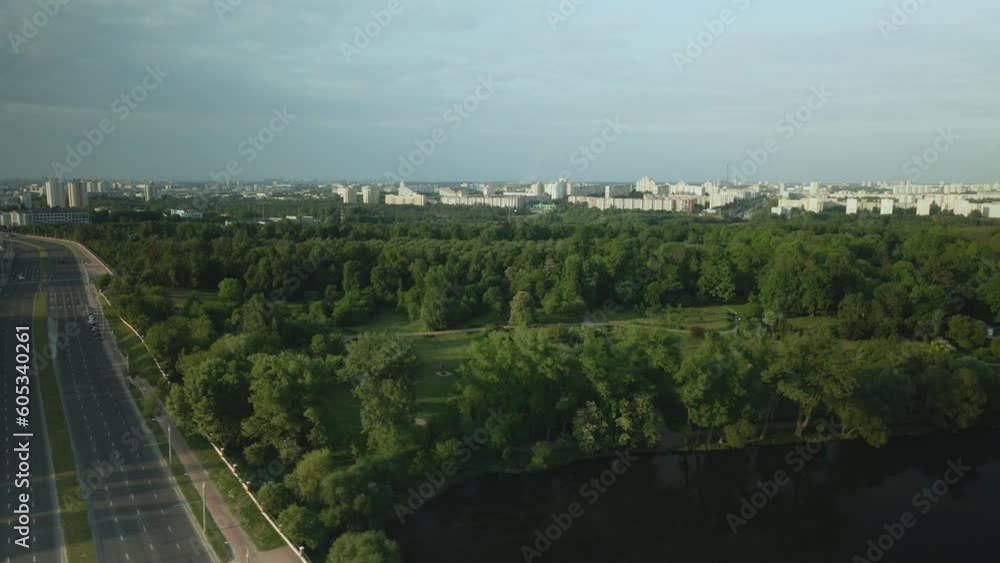 Flight over the city park. You can see the lake, on the horizon of the house. Near city highway. Aerial photography.