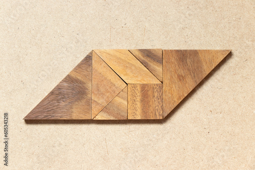 Wooden tangram in parallelogram shape on wood background