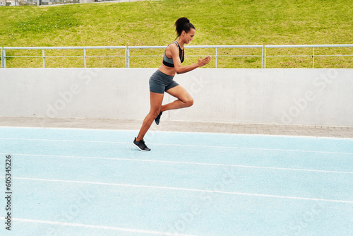 Woman, cardio and running on stadium track for training, physical exercise or workout. Active, fit or sporty female person, athlete or runner in sports run, race or competition for healthy wellness