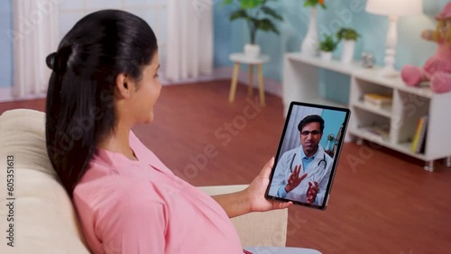 Shoulder shot of pregnant woman consulting doctor on video call at home - concept Telemedicine, Virtual healthcare and Remote consultation.