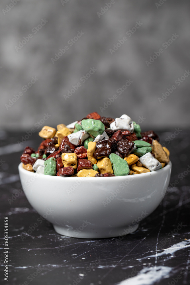 Colorful chocolate candy stones. Stone chocolate dragee in ceramic bowl on dark background. Small multi-colored candies Colorful chocolate candy stones. Stone chocolate dragee in ceramic bowl on dark background. Small multi-colored candies