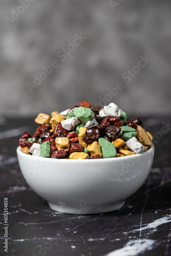 Colorful chocolate candy stones. Stone chocolate dragee in ceramic bowl on dark background. Small multi-colored candies