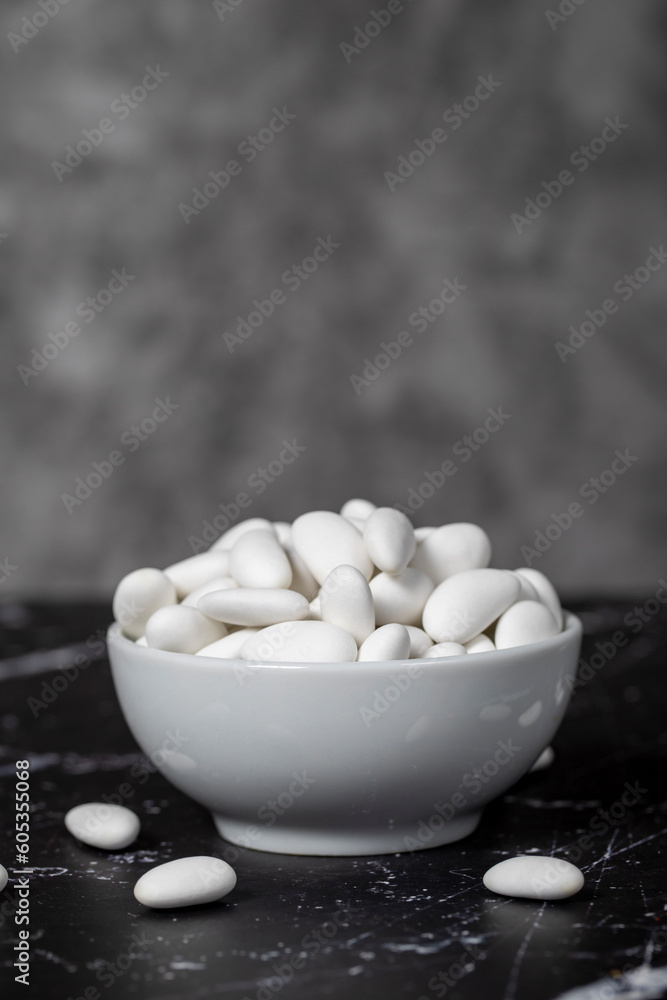 Almond candy. Sugar coated almond candy in ceramic bowl on dark background. Small multi-colored candies Almond candy. Sugar coated almond candy in ceramic bowl on dark background. Small multi-colored candies
