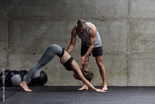 A muscular man assisting a fit woman in a modern gym as they engage in various body exercises and muscle stretches  showcasing their dedication to fitness and benefiting from teamwork and support