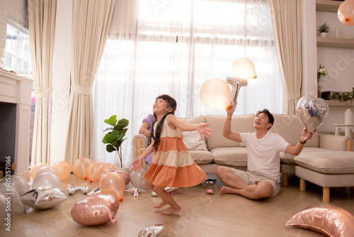 Happy asian family father and mother and daughter play balloon with enjoy and fun while celebration in living room at home, dad and mom and kid relax and recreation, lifestyles and relation concept.