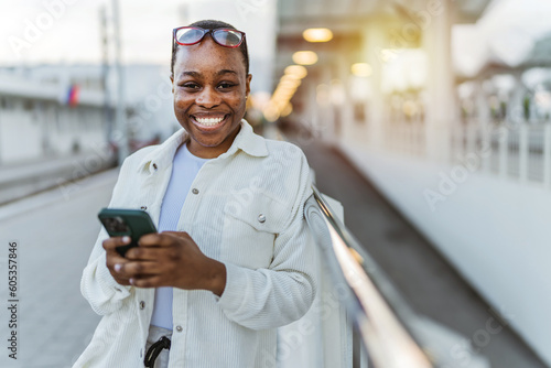 Cropped shot of a African American young woman waiting on station and using smart phone. © Jelena Stanojkovic