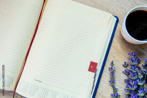 Outdoor leather notepad, fountain pen, cup with coffee and flowers (lavender) on the desktop. 