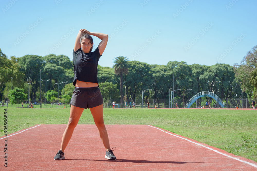 young latin woman outdoors stretching arms and shoulders before training.