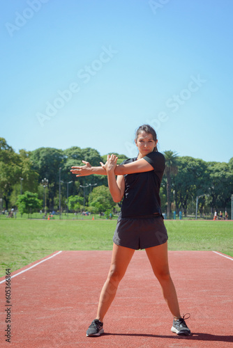 young woman on track stretching warming up before training, vertical image. © SETO fotografias