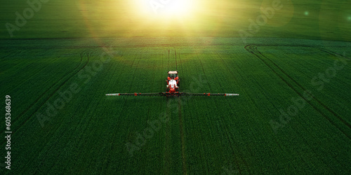 Tractor spraying pesticides on wheat  field with sprayer  in spring.