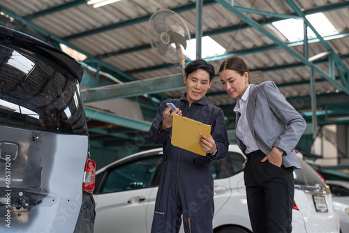 Asian car mechanic man in uniform explaining checklist car maintenance and repair to woman client at auto car garage service