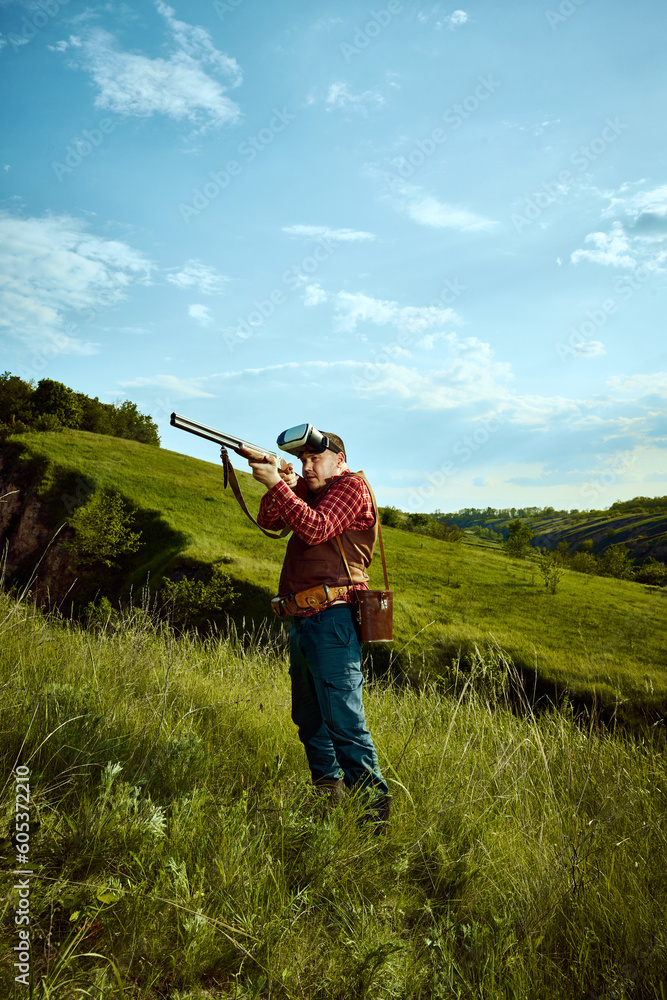 Portrait with adult man using VR glasses to hunting over landscapes background. Online hunting. Concept of virtual reality, video games Portrait with adult man using VR glasses to hunting over landscapes background. Online hunting. Concept of virtual reality, video games