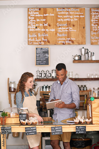Coffee shop owners, tablet and teamwork of people, manage orders and discussion in store. Waiters, black man and happy woman in cafe with technology for inventory, stock check and managing sales.