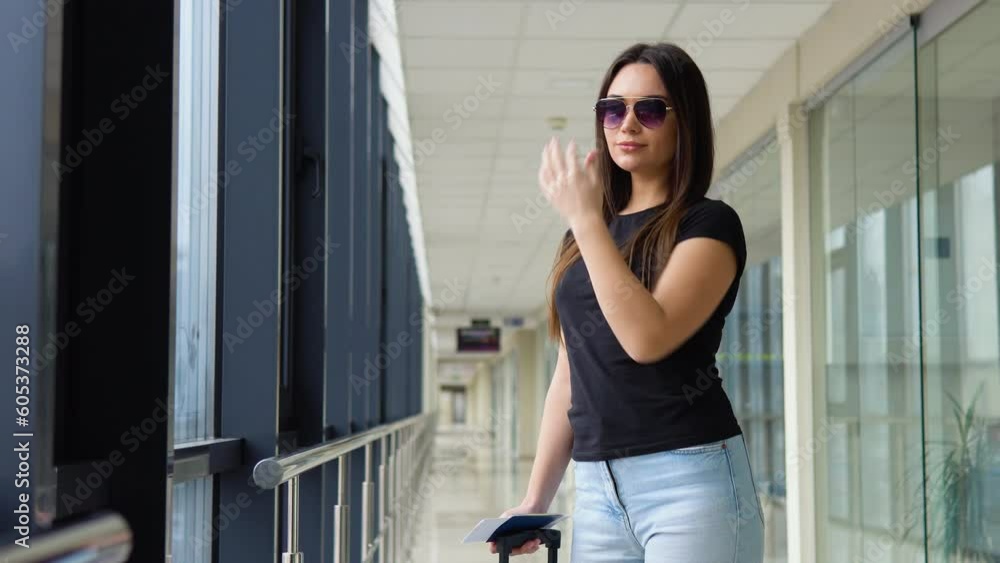 Woman puts on a sunglasses, holding passport and boarding passes ticket in airport hallway Woman puts on a sunglasses, holding passport and boarding passes ticket in airport hallway