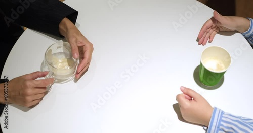 two female colleagues talking in the office and drinking coffee sitting by the table. One woman explaining something with gesture. No face seen, only hands. High quality 4k footage