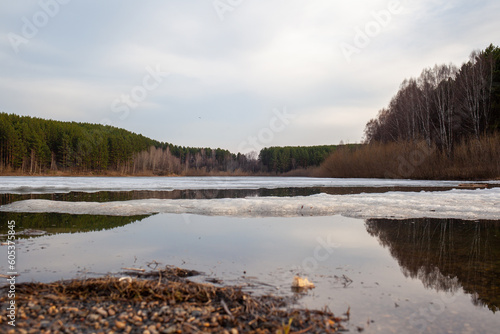 Spring streams in nature. The snow melts in a large lake and clear streams run. Nature against the blue sky  lakes and forests. Beautiful natural background.