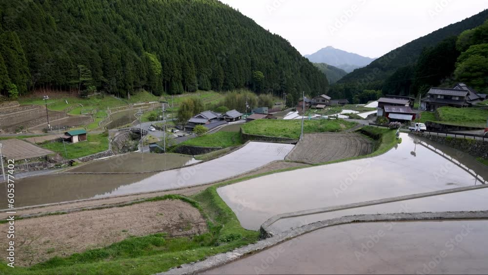 View of flooded rice fields in terraced landscape by small mountain village View of flooded rice fields in terraced landscape by small mountain village