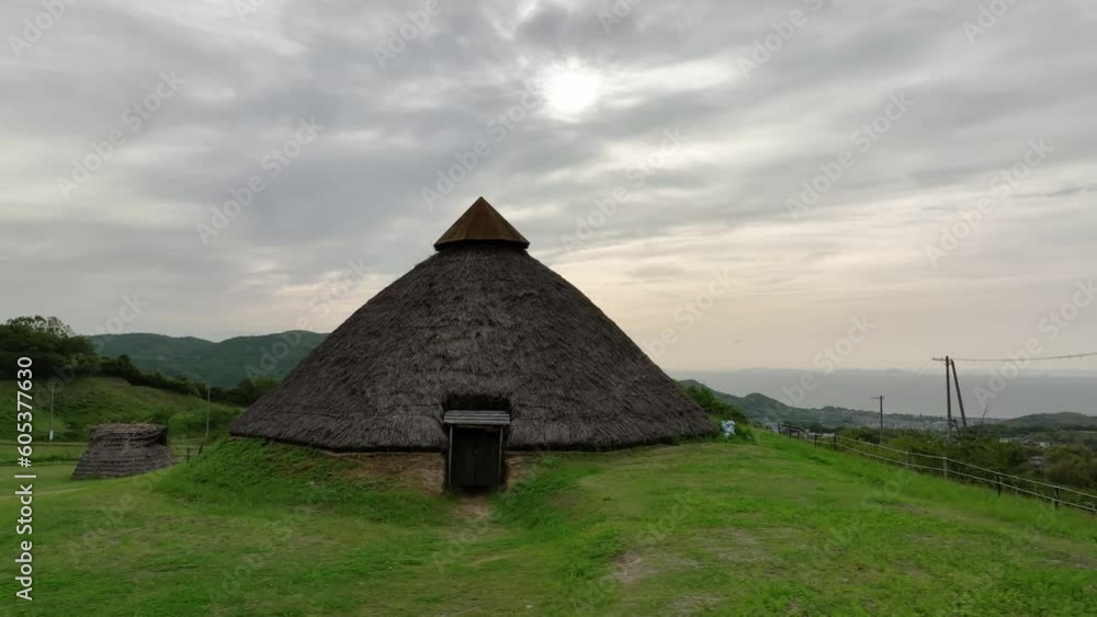 Entrance to historic thatched-roof hut in Jomon village on green grass Entrance to historic thatched-roof hut in Jomon village on green grass