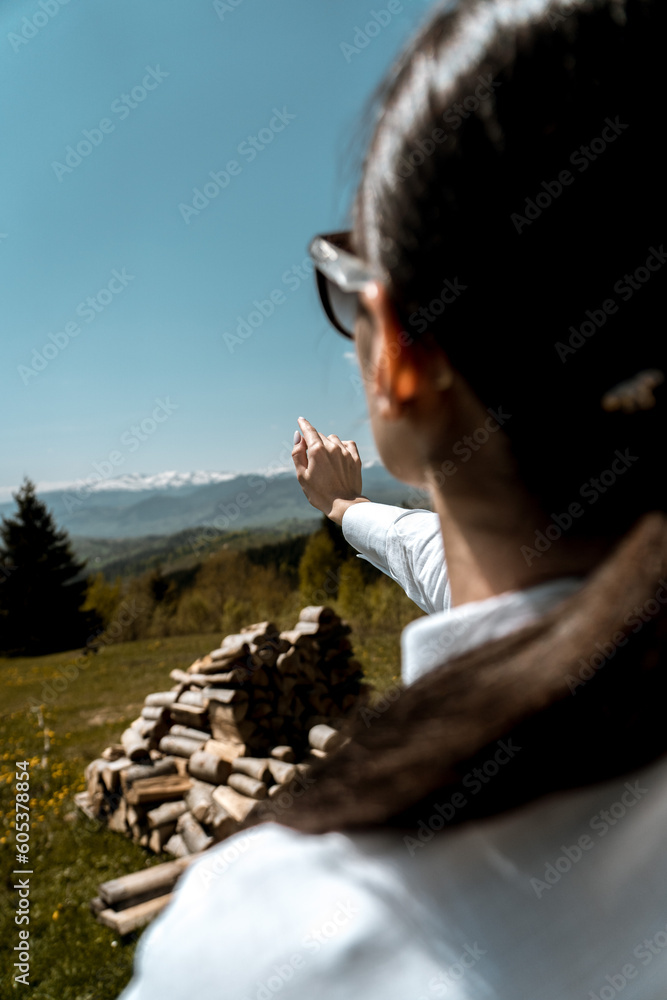 Fototapeta premium Pretty woman in a white shirt and glasses posing against the backdrop of a modern mountain hotel.Businessman woman concept