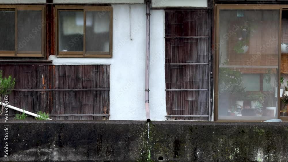 Water flows from drain pipe on historic wooden Japanese house in rain Water flows from drain pipe on historic wooden Japanese house in rain