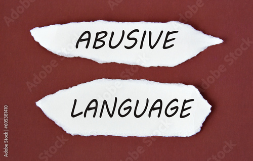 ABUSIVE LANGUAGE - words on white torn pieces of paper on a burgundy background