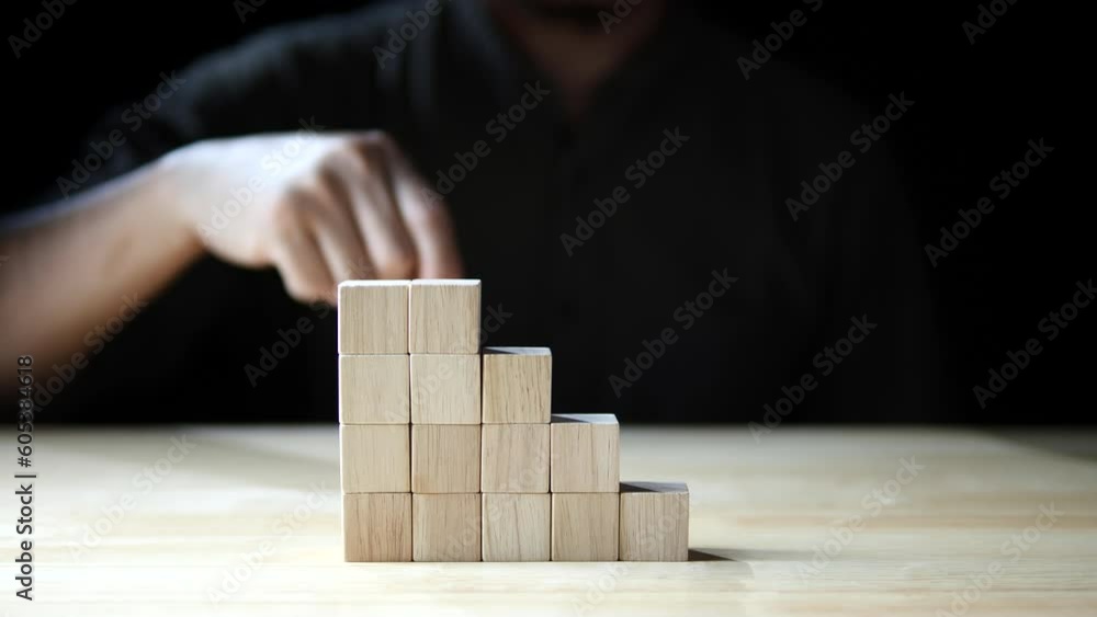 Businessman hand stacking wood block as step stair, business development, business growth success on dark background. Concept of Business growth, Financial planning, Investment, Strategy
