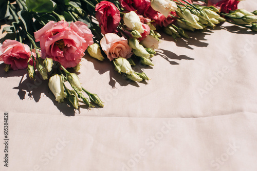 Gently pink eustomas on the beige background. Natural background with a bouquet of flowers with copy space. Flat lay