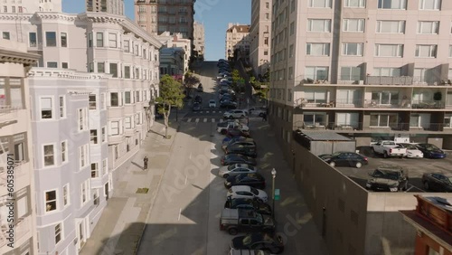 Cars parked along steep street. Vehicles passing road intersection in urban borough. San Francisco, California, USA