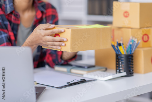 African American female fashion seller using computer checking ecommerce clothing store orders.young business woman entrepreneur working on laptop preparing SME online shipping delivery parcels boxes.