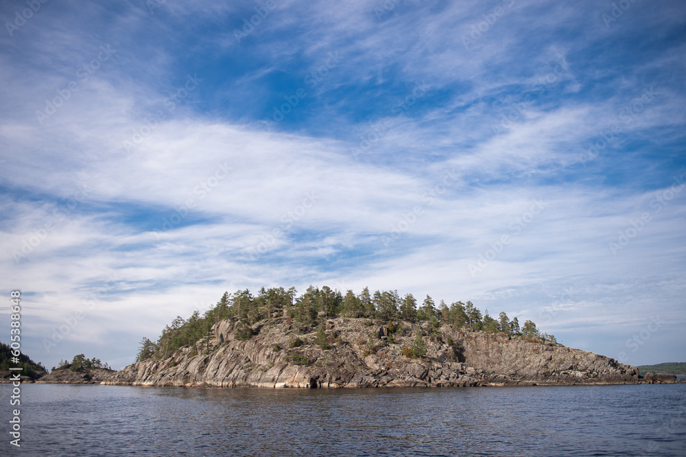 Rocky rocks in the lake on the background of a blue sky with clouds Rocky rocks in the lake on the background of a blue sky with clouds