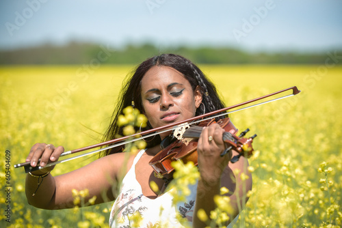 Lovely black woman playing violin in a rapeseed field