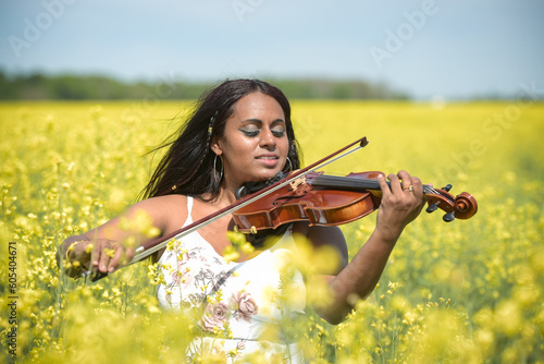 Lovely black woman playing violin in a rapeseed field