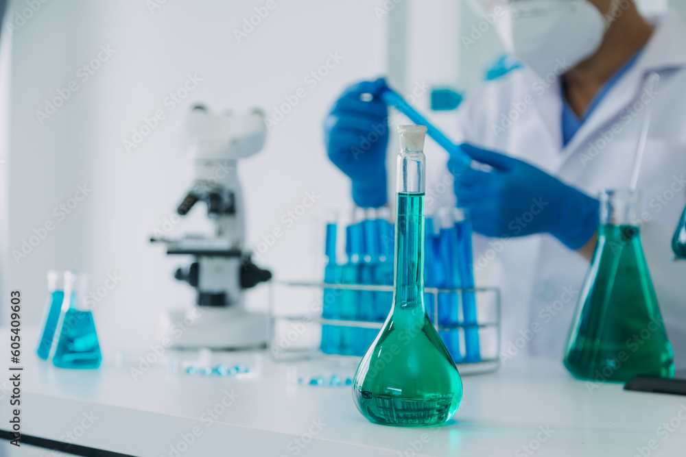 medical or scientific researcher researching and experimenting Multi-colored solution, vial and microscope In the laboratory or in the laboratory by wearing blue gloves and white clothing completely. medical or scientific researcher researching and experimenting Multi-colored solution, vial and microscope In the laboratory or in the laboratory by wearing blue gloves and white clothing completely.