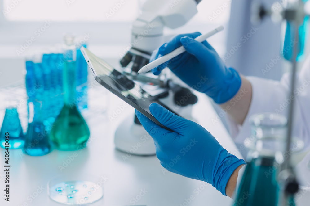 medical or scientific researcher researching and experimenting Multi-colored solution, vial and microscope In the laboratory or in the laboratory by wearing blue gloves and white clothing completely. medical or scientific researcher researching and experimenting Multi-colored solution, vial and microscope In the laboratory or in the laboratory by wearing blue gloves and white clothing completely.